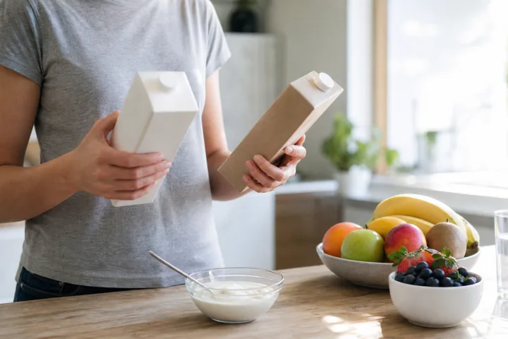 persona che confronta confezioni alimentari neutre accanto a yogurt e frutta