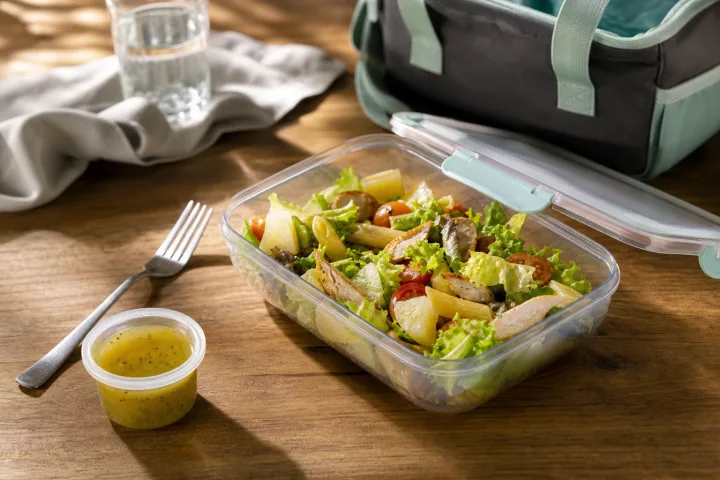 Lunch box con insalata pronta servita e condimento separato su un tavolo di cucina